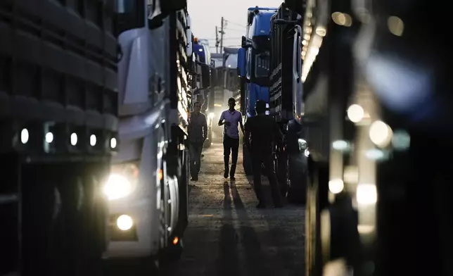 A truck driver walks between trucks carrying humanitarian aid just before they cross into the Gaza Strip at Erez crossing in southern Israel, Monday, Oct. 21, 2024. (AP Photo/Tsafrir Abayov)