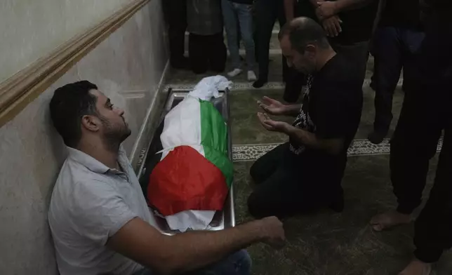 Mourners take the last look at the body of Sameh al-Asali, 38, a Palestinian worker from Gaza who had been stranded in the territory since the war broke out and was killed by a rocket during Tuesday's night's Iranian strike toward Israel, during his funeral in the West Bank city of Jericho, Wednesday, Oct. 2, 2024. (AP Photo/Nasser Nasser)