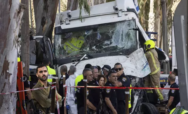 Israeli police and rescue services inspect the site where a truck driver rammed into a bus stop near an army base, wounding dozens of people, according to Israel's Magen David Adom rescue service in Ramat Hasharon, Israel, Sunday, Oct. 27, 2024. (AP Photo/Oded Balilty)