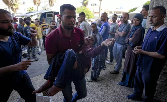 A Palestinian man carries an injured child after an Israeli airstrike in Deir al Balah, Gaza Strip, Thursday, Oct. 10, 2024. (AP Photo/Abdel Kareem Hana)