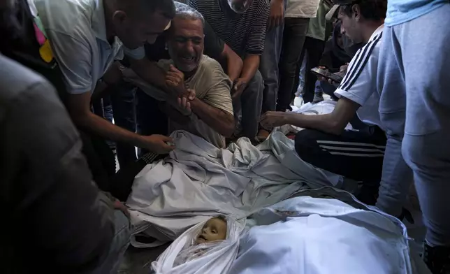 Palestinians mourn for relatives killed in the Israeli bombardment of the Gaza Strip at a hospital morgue in Deir al-Balah, Wednesday, Oct. 2, 2024. (AP Photo/Abdel Kareem Hana)