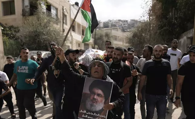 Palestinian activist Khairi Hanoun holds up a poster of Hassan Nasrallah, the leader of Hezbollah who was killed by an Israeli strike in September, while mourning Rayan al-Sayed, a Palestinian killed in an Israeli raid Monday in the West Bank city of Jenin, during Al-Sayed's funeral, Tuesday, Oct. 15, 2024. (AP Photo/Majdi Mohammed)