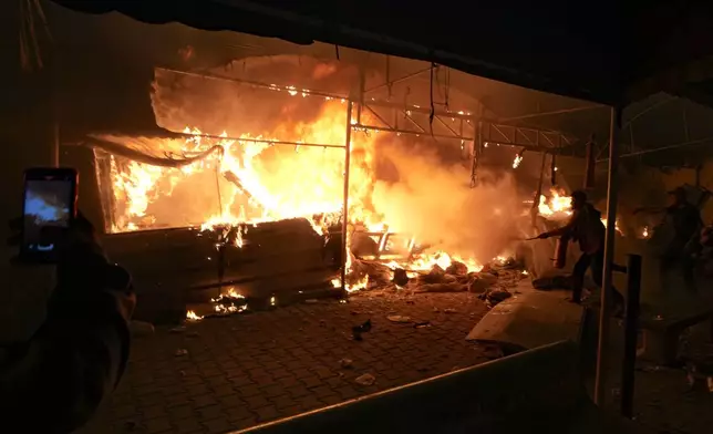 Palestinians try to extinguish fire caused by an Israeli strike that hit a tent area in the courtyard of Al Aqsa Martyrs hospital in Deir al-Balah, Gaza Strip, Monday, Oct. 14, 2024. (AP Photo/Abdel Kareem Hana)