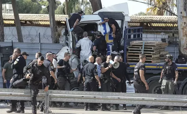 Israeli police climb on a truck that rammed into a bus stop near the headquarters of Israel's Mossad spy agency, wounding dozens of people, according to Israel's Magen David Adom rescue service in Tel Aviv, Israel, Sunday, Oct. 27, 2024. (AP Photo/Oded Balilty)