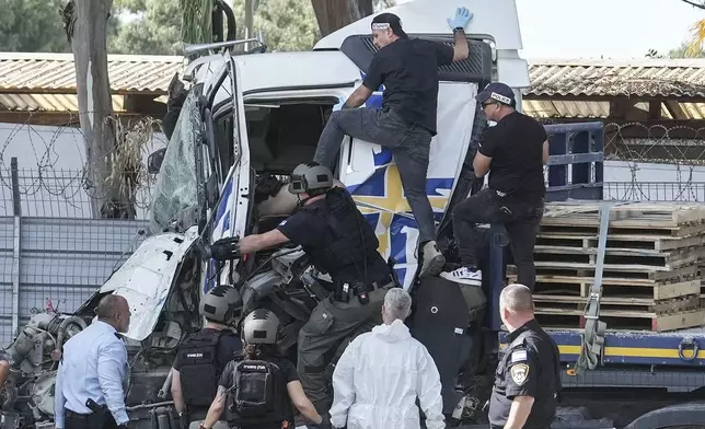 Israeli police climb on a truck to inspect the body of a driver that rammed into a bus stop near the headquarters of Israel's Mossad spy agency, wounding dozens of people, according to Israel's Magen David Adom rescue service in Tel Aviv, Israel, Sunday, Oct. 27, 2024. (AP Photo/Oded Balilty)