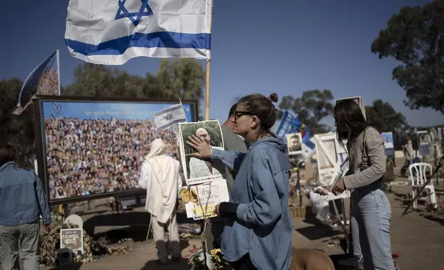 A woman pauses to touch the memorial marker of her loved one, Bar Lior Nakmuli, at the site of the Nova music festival, where hundreds of revelers were killed or kidnapped by Hamas, on the Jewish holiday of Simchat Torah, marking one year in the Hebrew calendar since the attack, near Kibbutz Re'im, southern Israel near the Gaza Strip, Thursday, Oct. 24, 2024. (AP Photo/Maya Alleruzzo)