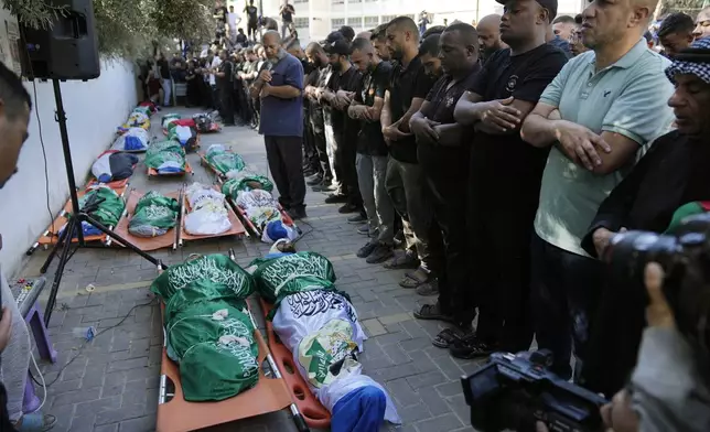 Draped in the Palestinian, Hamas and Islamic Jihad flags, mourners pray by the bodies of 18 Palestinians who were killed in an Israeli airstrike during their funeral in Tulkarem, Friday, Oct. 4, 2024. (AP Photo/Nasser Nasser)