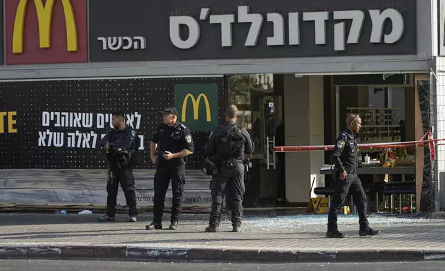 Police officers examine the scene of a stabbing and shooting attack where Israel's Magen David Adom rescue service said one person was killed and several others were wounded in Beersheba, Israel, Sunday, Oct. 6, 2024. (AP Photo/Tsafrir Abayov)