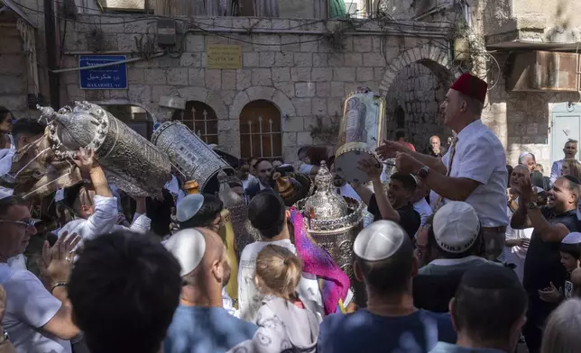 Jewish revelers dance in a circle during the holiday of Simchat Torah, on the first anniversary on the Jewish calendar of the day Hamas militants attacked Israel, in Jerusalem, Thursday Oct. 24, 2024. (AP Photo/Ohad Zwigenberg)