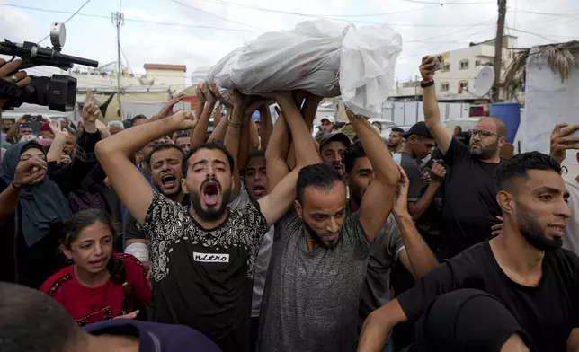 Palestinians mourn as they carry the body of a relative killed in the Israeli bombardment of the Gaza Strip at a hospital in Deir al-Balah, Tuesday, Oct. 8, 2024. (AP Photo/Abdel Kareem Hana)