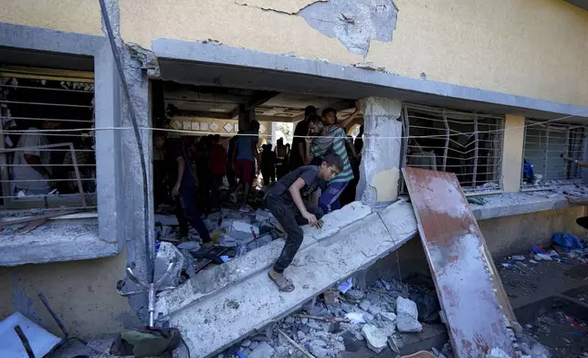 Palestinians search for the bodies of their relatives killed in an Israeli bombardment of a school in Deir al-Balah, central Gaza Strip, Thursday, Oct. 10, 2024. (AP Photo/Abdel Kareem Hana)