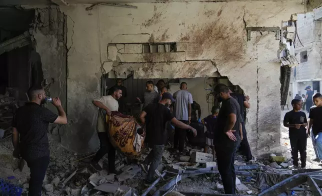 Palestinians examine the damage following an Israeli airstrike in the West Bank city of Tulkarem, which Palestinian health officials say killed 18 people and the Israeli military says took out a Hamas leader, on Friday, Oct. 4, 2024. (AP Photo/Nasser Nasser)