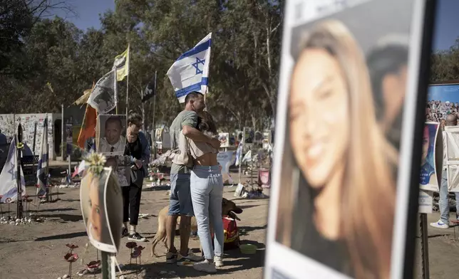 A family visits the the memorial marker of their loved one, Bar Lior Nakmuli, at the site of the Nova music festival, where hundreds of revelers were killed or kidnapped by Hamas, on the Jewish holiday of Simchat Torah, marking one year in the Hebrew calendar since the attack, near Kibbutz Re'im, southern Israel near the Gaza Strip, Thursday, Oct. 24, 2024. (AP Photo/Maya Alleruzzo)