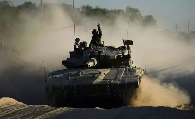 An Israeli soldier waves from a moving tank near the Israeli-Gaza border in southern Israel, Monday, Oct. 21, 2024. (AP Photo/Tsafrir Abayov)