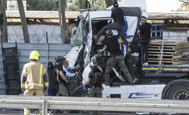 Israeli police climb on a truck to inspect the body of a driver that rammed into a bus stop near the headquarters of Israel's Mossad spy agency, wounding dozens of people, according to Israel's Magen David Adom rescue service in Tel Aviv, Israel, Sunday, Oct. 27, 2024. (AP Photo/Oded Balilty)