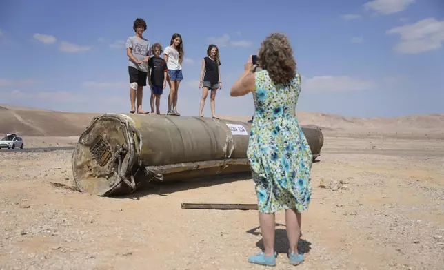 People take their photos with the debris of an Iranian missile intercepted by Israel, near Arad, southern Israel, Oct. 2, 2024. (AP Photo/Ohad Zwigenberg)