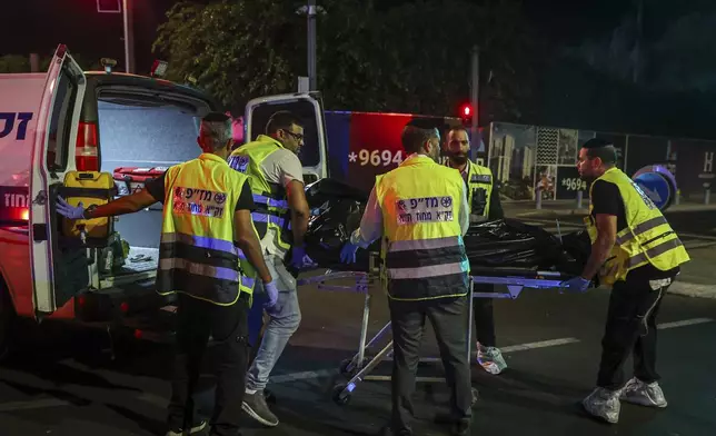 Members of Zaka Rescue and Recovery team load a dead person into an ambulance following a shooting attack in Jaffa, a mixed Arab-Jewish area of Tel Aviv, Israel, Tuesday, Oct. 1, 2024. (AP Photo/Itai Ron)