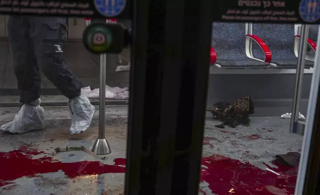 Israeli forensic technicians work around blood in a light rail car following a shooting attack in Jaffa, a mixed Arab-Jewish area of Tel Aviv, Israel, Tuesday, Oct. 1, 2024. (AP Photo/Itai Ron)