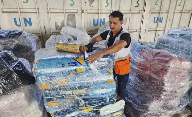 FILE - United Nations and Red Crescent workers prepare the aid for distribution to Palestinians at UNRWA warehouse in Deir Al-Balah, Gaza Strip, on Monday, Oct. 23, 2023. (AP Photo/Hassan Eslaiah, File)