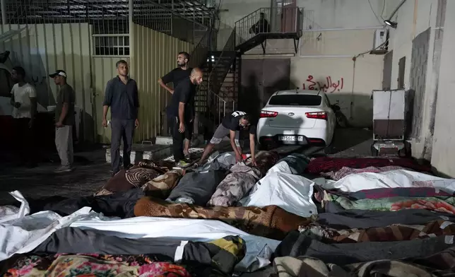 FILE - Palestinians check the bodies of their relatives killed in an Israeli bombardment of UNRWA school at Nusseirat refugee camp, in front of the morgue of al-Aqsa Martyrs hospital in Deir al-Balah, central Gaza Strip, early Thursday, June 6, 2024. (AP Photo/Abdel Kareem Hana, File)