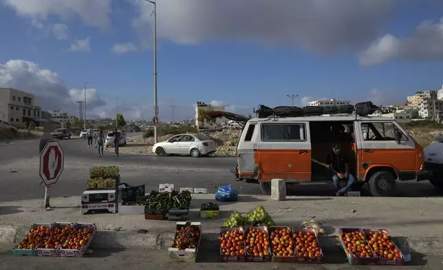 A Palestinian street vendor waits for customers while he displays vegetables for sale in the weekly market at the eastern outskirts of the West Bank city of Nablus Monday, Sept. 16, 2024. (AP Photo/Nasser Nasser)