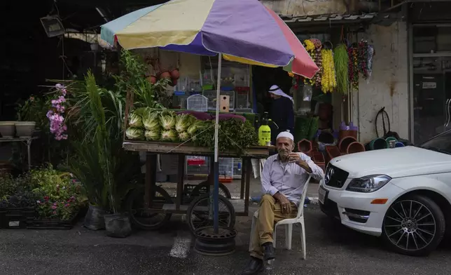 A Palestinian street vendor sits by his cart that is loaded with vegetables while he waits for customers, in the West Bank city of Nablus Monday, Sept. 16, 2024. (AP Photo/Nasser Nasser)