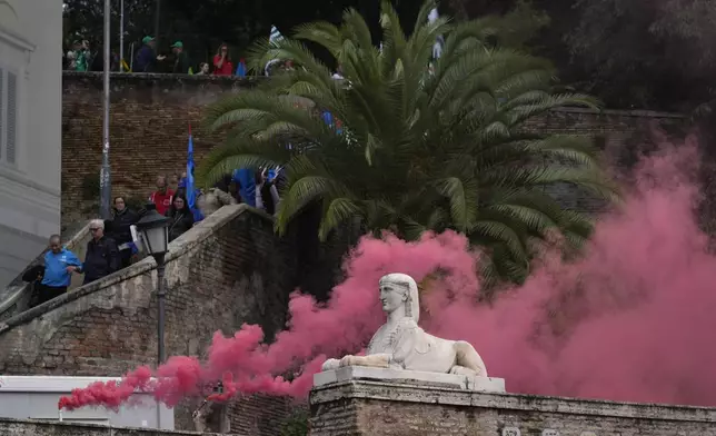 Workers of automotive sector burn flares as they arrive in Rome's Piazza Del Popolo Square during a demonstration on the occasion of their national strike, Friday, Oct. 18, 2024. (AP Photo/Gregorio Borgia)