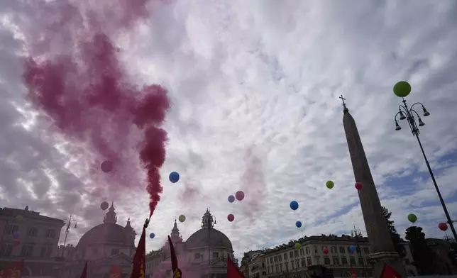 Workers of automotive sector burn flares in Rome's Piazza Del Popolo Square during a demonstration on the occasion of their national strike, Friday, Oct. 18, 2024. (AP Photo/Gregorio Borgia)