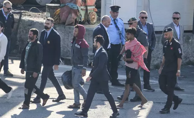 FILE - Migrant and security officials walk at the port of Shengjin, northwestern Albania. Wednesday, Oct. 16, 2024 after disembarking from the Italian navy ship Libra, carrying the first group of 16 migrants intercepted in international waters. (AP Photo/Vlasov Sulaj, File)