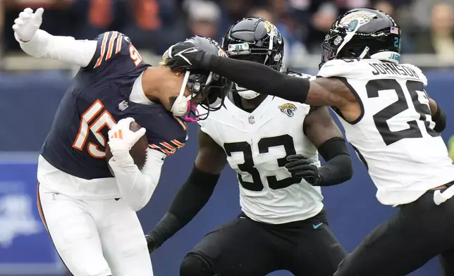 Chicago Bears wide receiver Rome Odunze (15) is tackled by Jacksonville Jaguars linebacker Devin Lloyd (33) and Jaguars safety Antonio Johnson (26) during an NFL football game at the Tottenham Hotspur stadium between the Jacksonville Jaguars and Chicago Bears in London, Sunday, Oct. 13, 2024. (AP Photo/Alastair Grant)