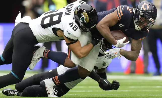 Chicago Bears wide receiver DJ Moore (2) is tackled by Jacksonville Jaguars linebacker Chad Muma (48) during an NFL football game at the Tottenham Hotspur stadium between the Jacksonville Jaguars and Chicago Bears in London, Sunday, Oct. 13, 2024. (AP Photo/Alastair Grant)