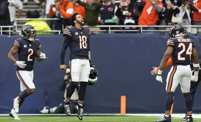 Chicago Bears quarterback Caleb Williams (18) celebrates after Bears wide receiver Keenan Allen (13) scored his side's third touchdown during the third quarter of an NFL football game at the Tottenham Hotspur stadium between the Jacksonville Jaguars and Chicago Bears in London, Sunday, Oct. 13, 2024. (AP Photo/Steve Luciano)