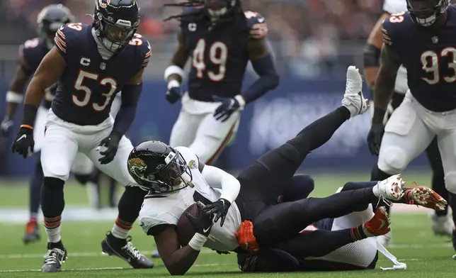 Jacksonville Jaguars running back Travis Etienne Jr. (1) is tackled during an NFL football game at the Tottenham Hotspur stadium between the Jacksonville Jaguars and Chicago Bears in London, Sunday, Oct. 13, 2024. (AP Photo/Ian Walton)