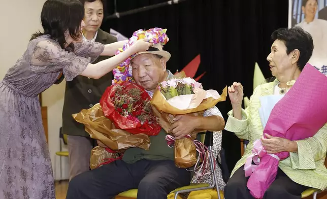 Former Japanese death-row inmate Iwao Hakamada, center, with his sister Hideko Hakamada, right, receive a bouquet of flowers during a gathering of supporters in Shizuoka, central Japan on Oct. 14, 2024. (Kyodo News via AP)