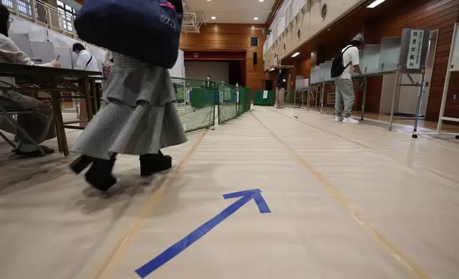 A woman walks towards voting booths at a polling station for Japan's lower house election in Tokyo, Japan, Sunday, Oct. 27, 2024. (AP Photo/Hiro Komae)