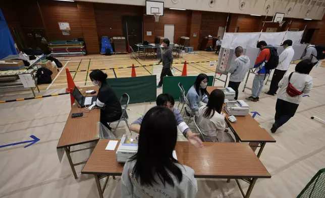 Election staff members help voters at a polling station for Japan's lower house election in Tokyo, Japan, Sunday, Oct. 27, 2024. (AP Photo/Hiro Komae)