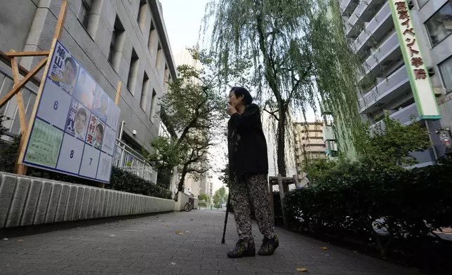 A woman looks at a billboard with candidates campaign posters for Japan's lower house election installed at a polling station in Tokyo, Japan, Sunday, Oct. 27, 2024. (AP Photo/Hiro Komae)