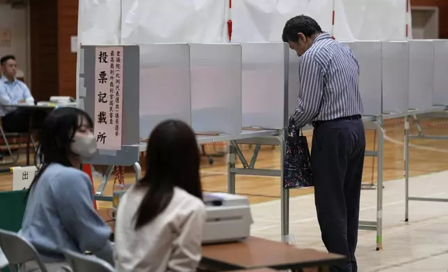 A voter prepares to cast his ballot at a polling station for Japan's lower house election in Tokyo, Japan, Sunday, Oct. 27, 2024. (AP Photo/Hiro Komae)