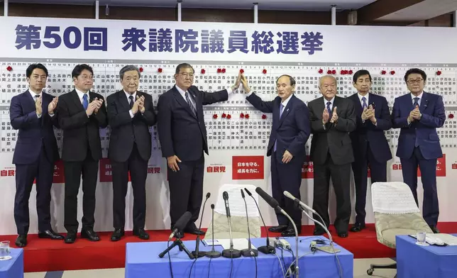 Japan's Prime Minister and president of the Liberal Democratic Party (LDP) Shigeru Ishiba, fourth from left, and the party's other senior members pose for a photo in front of the LDP candidates’ names of the lower house election seen on the board, at the party's headquarters Sunday, Oct. 27, 2024 in Tokyo, (Takashi Aoyama/Pool Photo via AP)