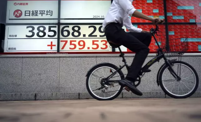 A person rides a bicycle in front of an electronic stock board showing Japan's Nikkei index at a securities firm Thursday, Oct. 3, 2024, in Tokyo. (AP Photo/Eugene Hoshiko)