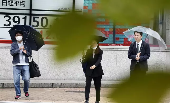 People walk in front of an electronic stock board showing Japan's Nikkei index at a securities firm, Wednesday, Oct. 9, 2024, in Tokyo. (AP Photo/Eugene Hoshiko)