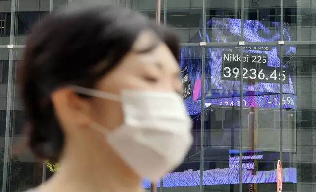 A person walks near an electronic stock board showing Japan's Nikkei index at a securities firm Wednesday, Oct. 16, 2024, in Tokyo. (AP Photo/Eugene Hoshiko)