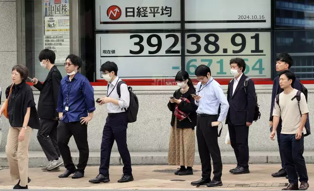 People stand in front of an electronic stock board showing Japan's Nikkei index at a securities firm Wednesday, Oct. 16, 2024, in Tokyo. (AP Photo/Eugene Hoshiko)