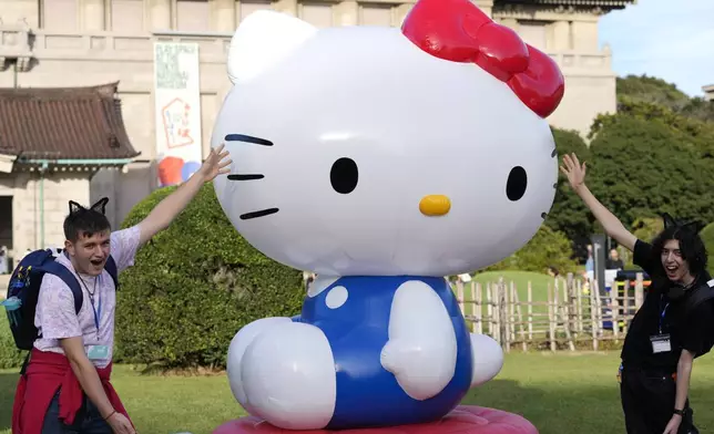 Tourists from Britain pose with Hello Kitty decoration at the Tokyo National Museum where the exhibition "As I change, so does she" is held, marking the 50th anniversary of Hello Kitty in Tokyo Wednesday, Oct. 30, 2024. (AP Photo/Shuji Kajiyama)