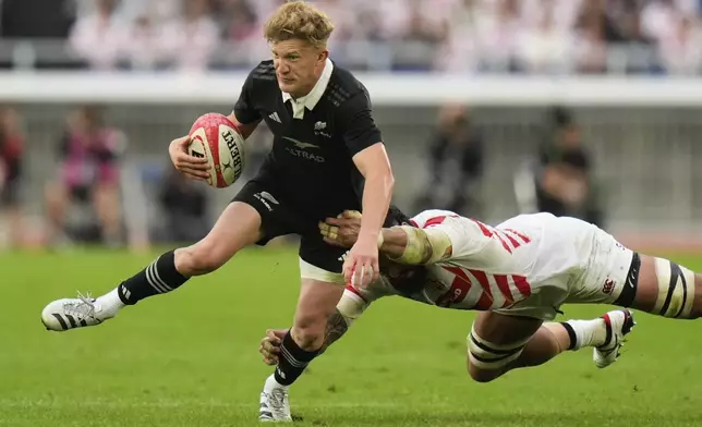 New Zealand's Damian McKenzie attempts to break a tackle during a rugby test match between the All Blacks and Japan at Nissan Stadium in Yokohama, near Tokyo, Saturday, Oct. 26, 2024. (AP Photo/Shuji Kajiyama)