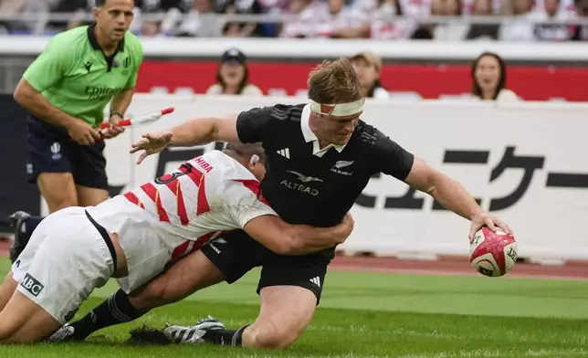 New Zealand's Sam Cane reaches out to score a try as Japan's Shuhei Takeuchi, left, attempts a tackle during a rugby test match between the All Blacks and Japan at Nissan Stadium in Yokohama, near Tokyo, Saturday, Oct. 26, 2024. (AP Photo/Shuji Kajiyama)