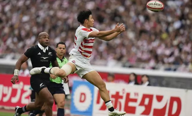 Japan's Yoshitaka Yazaki, right, attempts to catch the ball as New Zealand's Mark Tele'a watches during a rugby test match between the All Blacks and Japan at Nissan Stadium in Yokohama, near Tokyo, Saturday, Oct. 26, 2024. (AP Photo/Shuji Kajiyama)