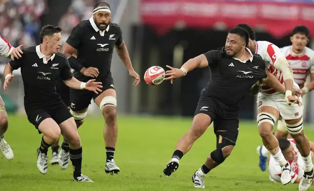 New Zealand's Asafo Aumua passes the ball to teammate Cam Roigard, left, during a rugby test match between the All Blacks and Japan at Nissan Stadium in Yokohama, near Tokyo, Saturday, Oct. 26, 2024. (AP Photo/Shuji Kajiyama)