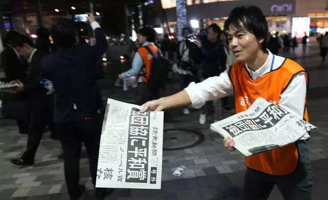 A worker of the Yomiuri Shimbun newspaper hands out copies of an extra version to passersby in Tokyo, Friday, Oct. 11, 2024, after Nihon Hidankyo, or the Japan Confederation of A- and H-Bomb Sufferers Organizations, won the Nobel Peace Prize. (AP Photo/Shuji Kajiyama)