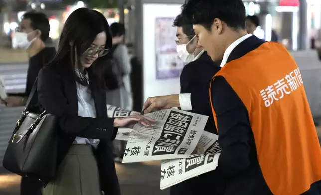 A worker of the Yomiuri Shimbun newspaper hands out copies of an extra version to passersby in Tokyo, Friday, Oct. 11, 2024, after Nihon Hidankyo, or the Japan Confederation of A- and H-Bomb Sufferers Organizations, won the Nobel Peace Prize. (AP Photo/Shuji Kajiyama)